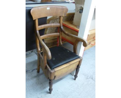 A late 19thC satin mahogany framed commode/elbow chair, having a bar back and drop-in seat with a modesty apron, raised on ri