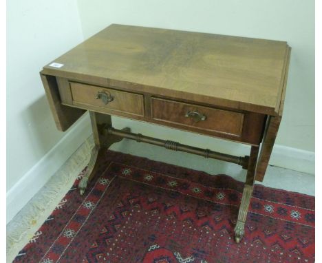 A mid 20thC figured walnut finished sofa style coffee table, raised on plank ends, splayed  feet and brass claw casters  19''