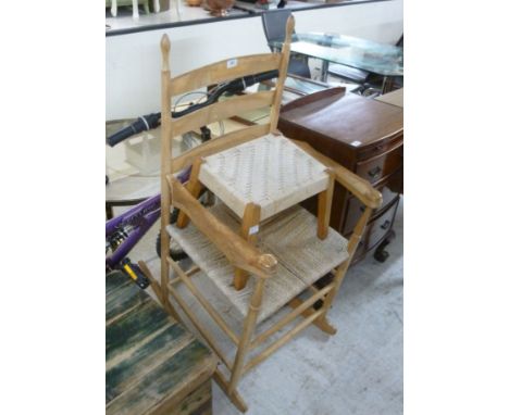 A modern light coloured beech framed ladderback, open arm rocking chair with a woven string seat raised on turned legs; and a