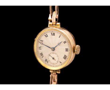 A 9ct early 20th century lady's manual wind wristwatch with 9ct expanding bracelet. The silvered engine turned 23mm dial with