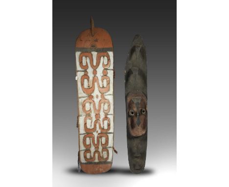 An Asmat shieldCasuarina Coast, Irian Jayawith carved stylised figures and a stylised snake finial, with pigment decoration a