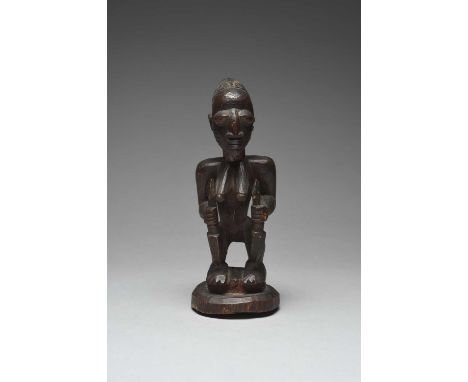 A Yoruba standing female figureAbeokuta, Nigeriawith a tied coiffure and holding a staff with an arrow head termimal in each 