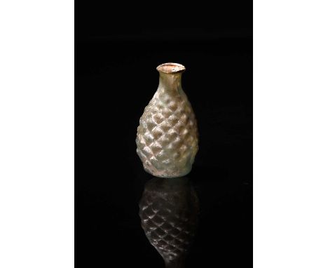 A Roman pale green glass pine cone flask circa 2nd - 3rd century AD the body blown in a two part mould with rows of diamond s