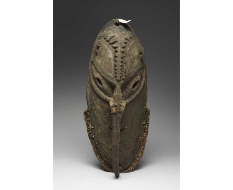A Sepik River mask Papua New Guineawith pierced eliptical eyes, ears and mouth, with a ridged long nose, with white and brown
