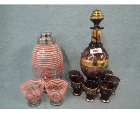 A red and gilt glass decanter and glasses, and a candy stiped cocktail shaker and glasses