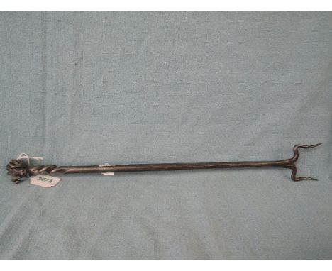 A wrought iron toasting fork with rams head decoration on the handle