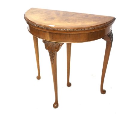 A  burr walnut demi-lune foldover card table. With carved frieze, raised on cabriole supports, L75cm x D37.5cm x H75.5cm