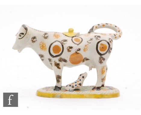 A small late 18th to early 19th Century Prattware cow creamer and cover with recumbent calf beneath, she with tan and brown s