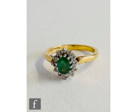 An 18ct hallmarked emerald and diamond cluster ring, central oval emerald within a diamond surround, weight 3.7g, ring size L