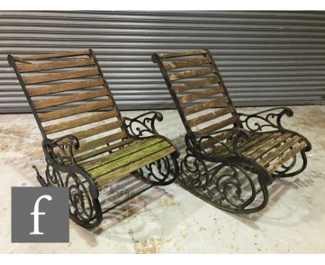 A pair of late 20th Century cast iron garden rocking chairs with decorative scroll side panels and with slatted wooden seats,
