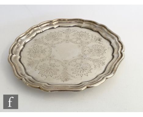 A hallmarked silver circular salver with engraved foliate decoration within raised, stepped plain borders, diameter 25cm, wei