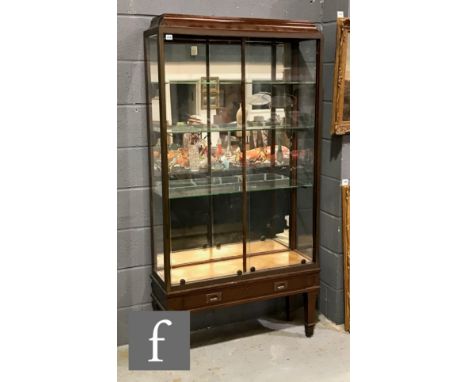 An early 20th Century mahogany shop display cabinet, the caddy shaped top above a bevelled brass bordered front and with glaz