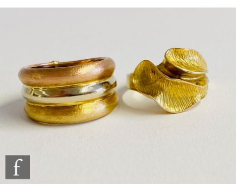 An 18ct ring with a two leaf design, weight 5g, with a similar unmarked tricoloured example, weight 3.5g, probably 9ct.(2). 