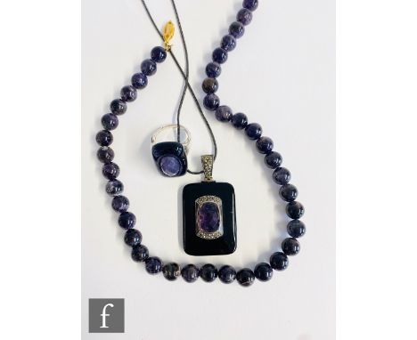 Three items of assorted amethyst set jewellery, a pendant with onyx border, a ring and a single row of beads. (3) 