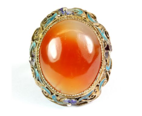 An interesting gilt metal and enamel adjustable ring set with a large cabochon cut cornelian.