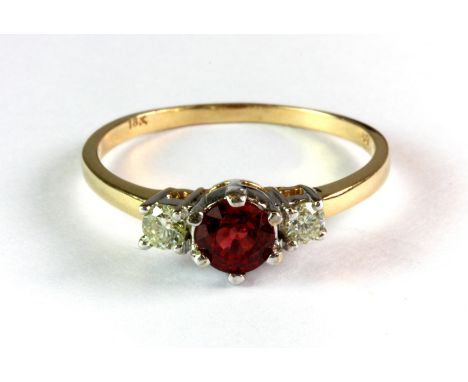 An 18ct yellow and white gold (stamped 18k) ring set with a brilliant cut ruby flanked by diamonds (O).