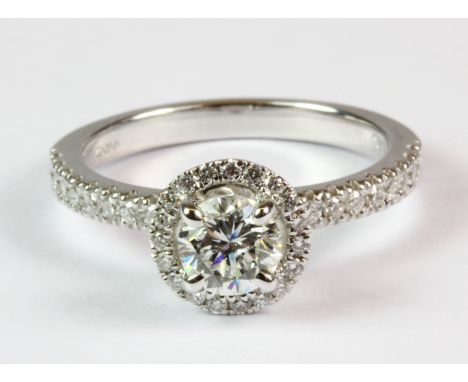 An 18ct white gold diamond halo ring with diamond set shoulders together with E. D. R. ring report (M.5).