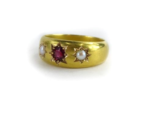 A ruby and seed pearl gypsy ring, with central ruby flanked by two seed pearls, each in star setting on a polished yellow met