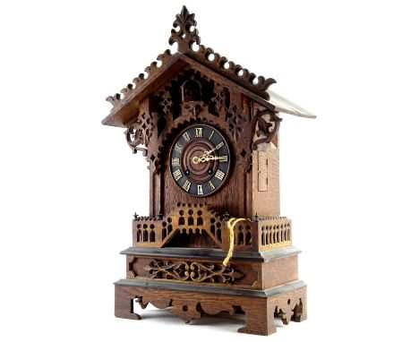 A 19th/ early 20thC Black Forest cuckoo clock, the dial with Roman Numerals, the case with pierced Gothic style decoration, l