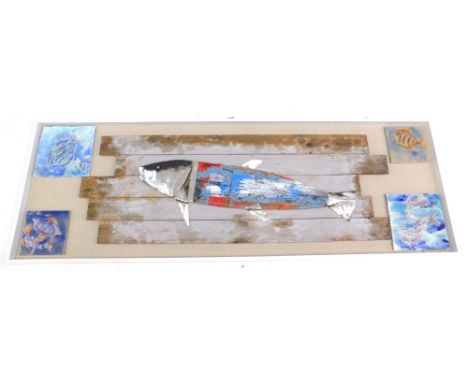 Continental School. Wooden sculpture of a fish, with distressed paint and metal embellishment, mounted on rough board surroun
