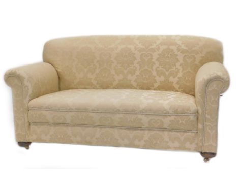 An Edwardian two seater sofa, re upholstered in beige and gold floral fabric on bun feet.