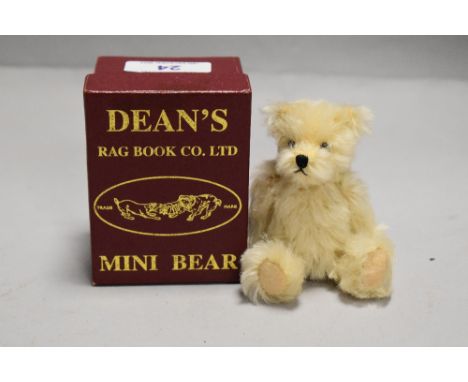 A 20th century miniature Dean's teddy bear with case and certificate having a light plush fur with movable limbs