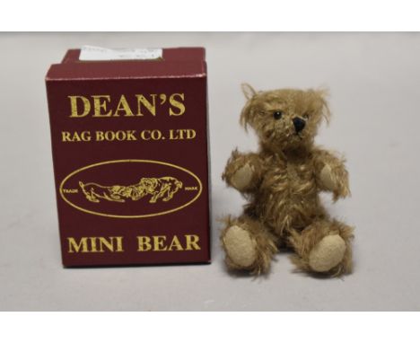 A 20th century miniature Dean's teddy bear with case and certificate having a light plush fur with movable limbs