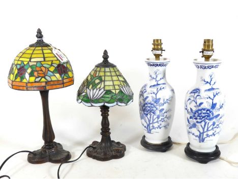 A reproduction Tiffany style table lamp and shade, the stained glass shade decorated with flowers on a bronzed composite base