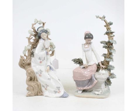 A Lladro porcelain figure of a geisha modelled leaning against a tree clutching a fan, h. 31cm, together with anotherThe seat