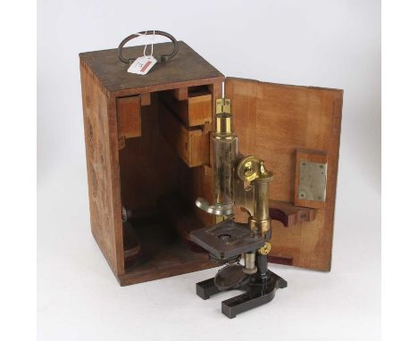An early 20th century lacquered brass and iron monocular microscope having a rack and pinion action above a concave mirror on