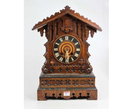 An early 20th century oak cased cuckoo clock having a Gothic style fret carved case, painted chapter ring with Roman numerals
