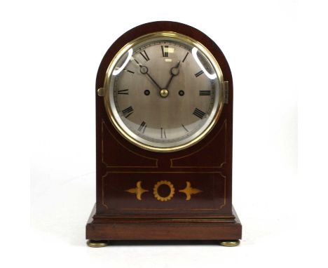 An Edwardian mahogany and satin wood inlaid dome top mantel clock, the silvered dial with Roman numerals, with a twin chain d