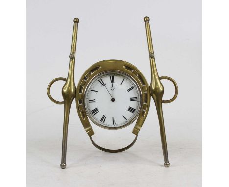 An early 20th century brass cased strut clock in the form of a horseshoe and yokes, having an enameled dial with Roman numera