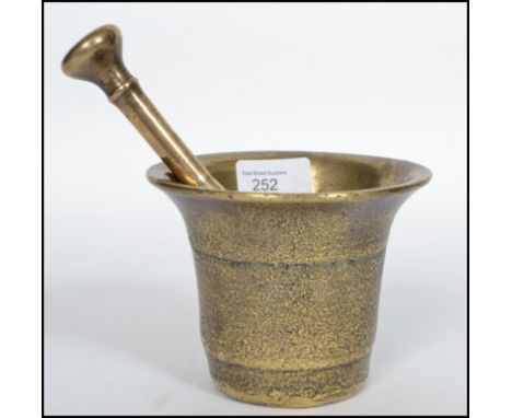 A heavy Oriental 18th century bronze pestle and mortar having a double ended pestle with bell shaped mortar. Measures 10cm hi