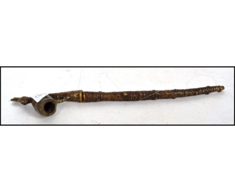 An early 20th century West African bronze ceremonial chieftains pipe having a naturalistic bark effect stem with the bowl in 