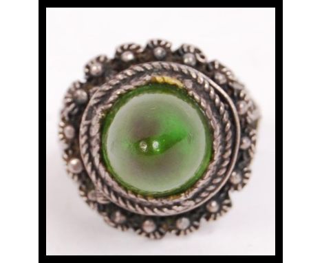 A fabulous asiatic silver white metal ladies ring with green conical protruding stone set over a hinged secret poison compart