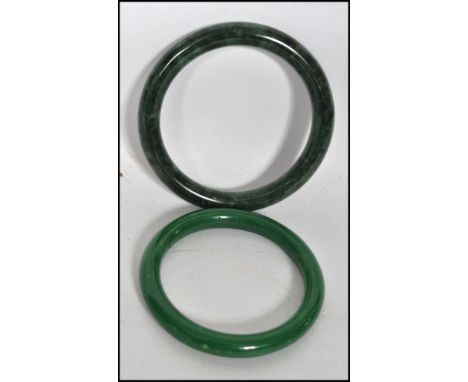 Two 20th century Chinese jade bangles of differing shades of green one being a very deep rich green.