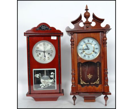A non matching pair of wooden cased wall clocks to include a 15 day wall clock and a Chinese made 31 day wall clock. Measures