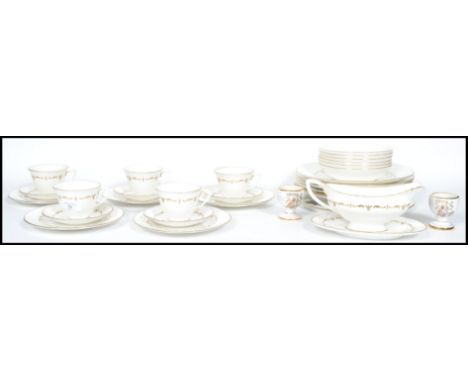 A part bone china gilt decorated on white ground dinner service by Royal Worcester consisting of plates, cups, bowls etc. All