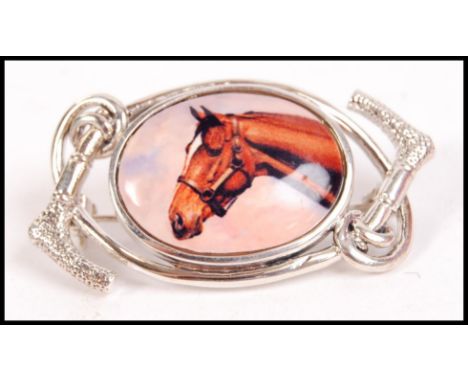 A ladies silver and enamel set dress brooch. The oval enamel pictorial of a horse ( hunting interest ) Total weight 11.2g / S