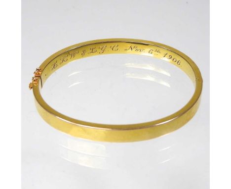 An Edwardian 14 carat gold bangle, of hinged design, inscribed and dated Nov. 6th 1906, 11g, 6cm wide, cased