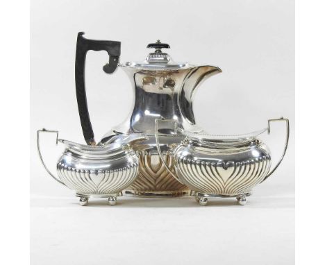 An Edwardian silver three piece tea service, with half gadrooned decoration, comprising a teapot, 22cm high, cream jug, 10cm 