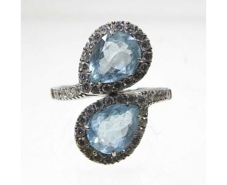 An 18 carat white gold and aquamarine cluster ring, of crossover design, set with two opposing heart shaped stones, within a 