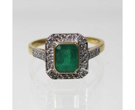 An unmarked emerald and diamond cluster ring, of Art Deco design, with a central baguette cut emerald and diamond shoulders, 