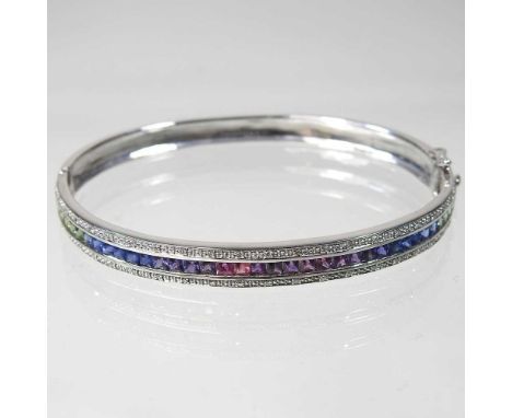 A 9 carat white gold and fancy sapphire bangle, of hinged design, set with a single row of multi coloured gems, 11g, 7cm wide