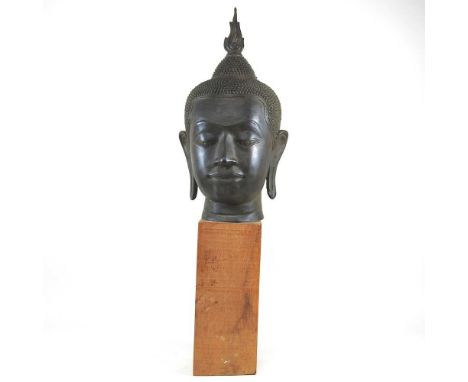 An Eastern bronze life-sized Buddha head, probably 20th century, mounted on a wooden base, 73cm high overall