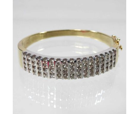 A 14 carat gold and diamond bangle, of hinged design, set with seventeen rows of four diamonds, the hinged clasp with safety 