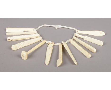 A child's ivory teething ring, with twelve individual teethers, including cricket bat, hammer and scissors.  