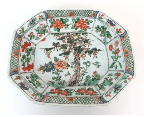 A Chinese famille verte octagonal deep dish painted with a pair of birds perched on a pine tree with gilt vine within panels 