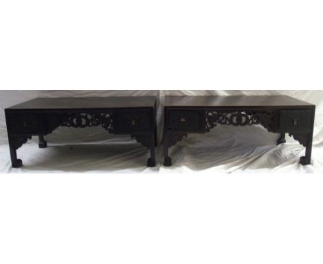 A pair of Chinese hardwood rectangular low tables carved with a pierced central frieze of entwined coins and foliage, flanked